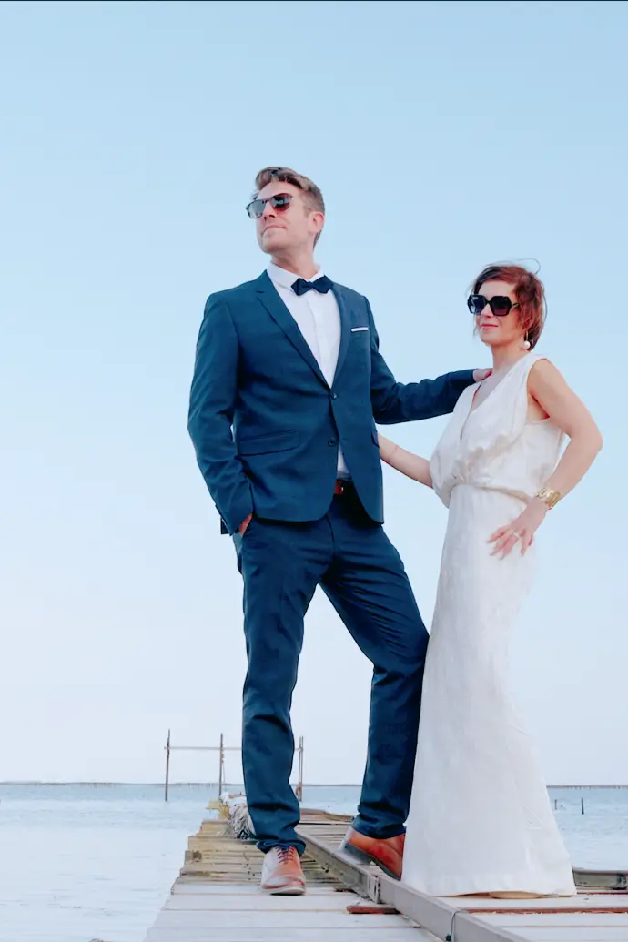 Emmanuel et Sébastien sur le ponton de l’étang de Thau lors de leur mariage au Château Sainte-Colombe-de-B, dans une image éditoriale élégante et lumineuse.
