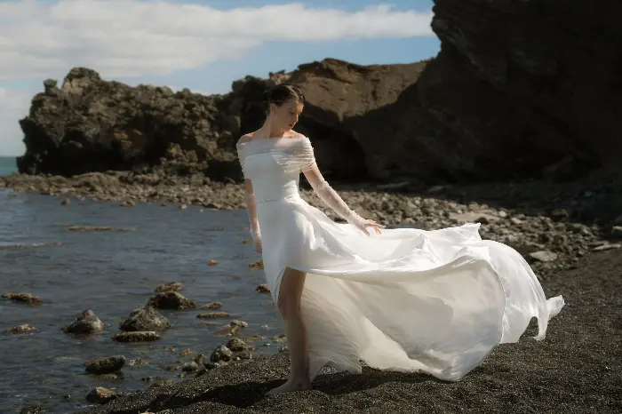 robe de mariée fluide en mouvement sur plage de sable noir en Provence