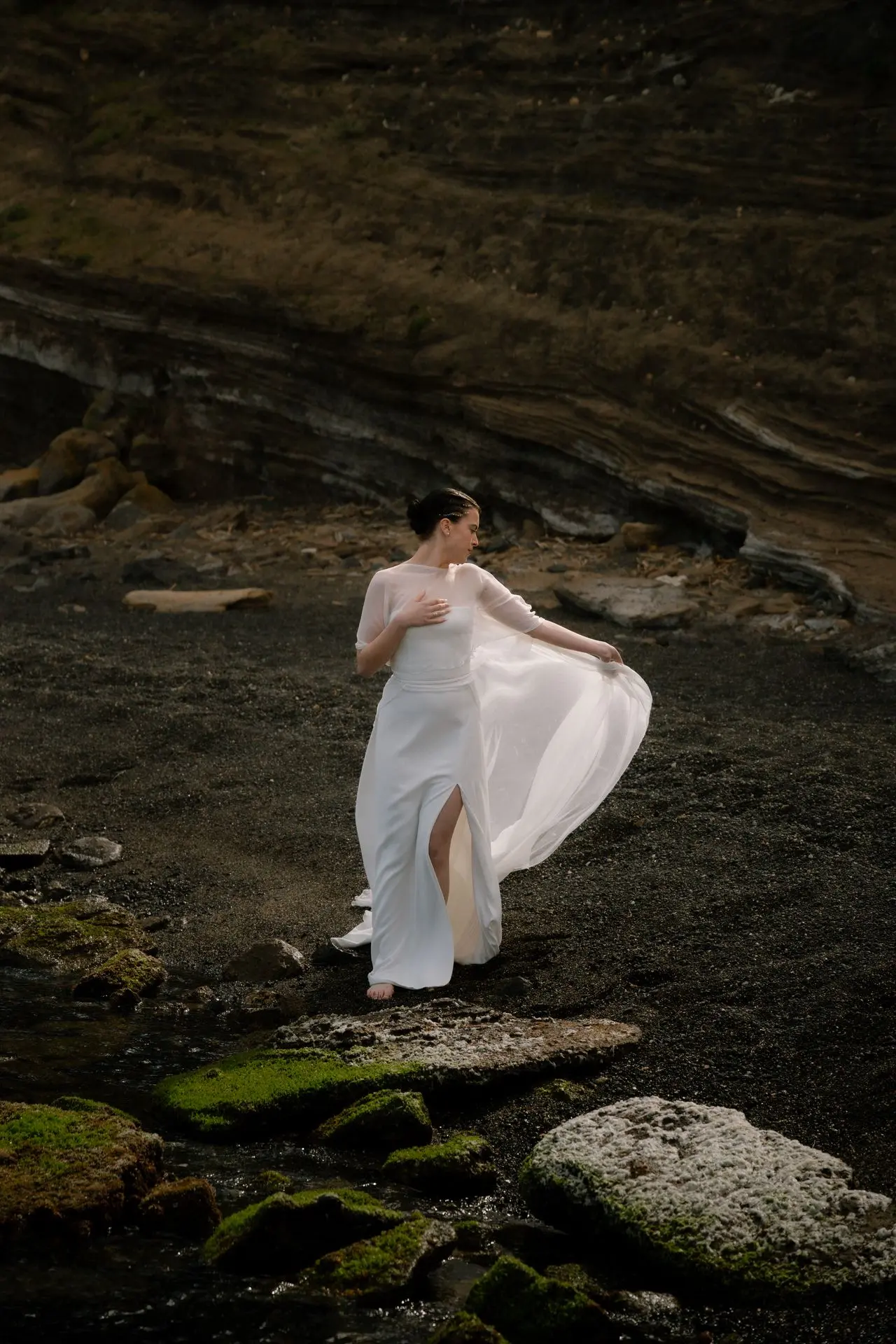 robe de mariée fluide en mouvement sur plage de sable noir en Provence
