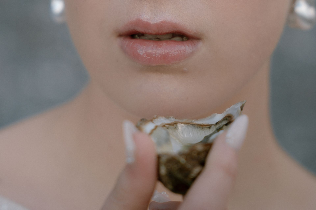 détail de mains avec huitre en lumière naturelle