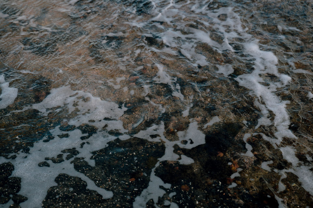 vague en mouvement sur sable noir avec texture minérale et écume