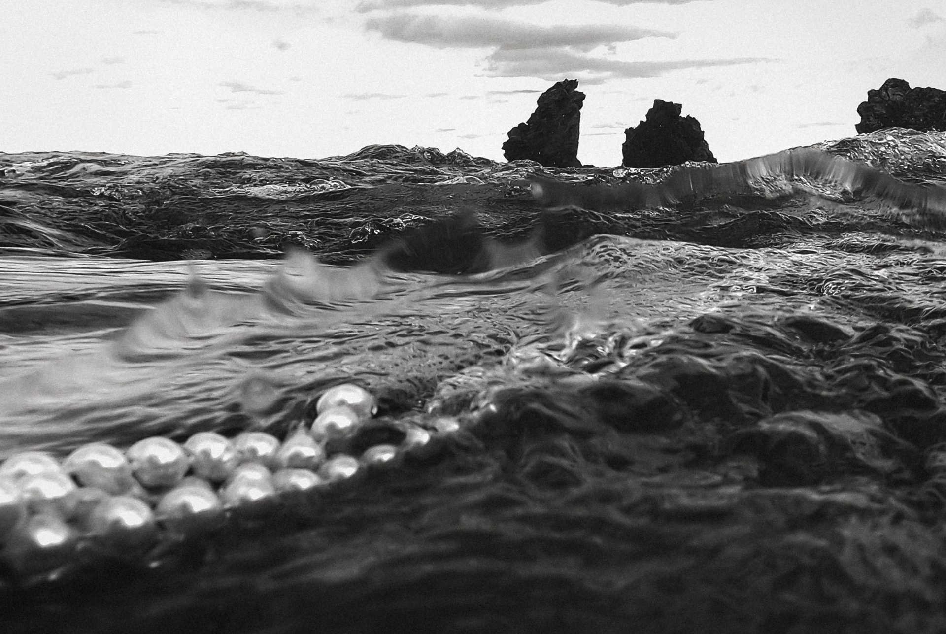 détail de perles dispersées dans l’eau sur plage volcanique